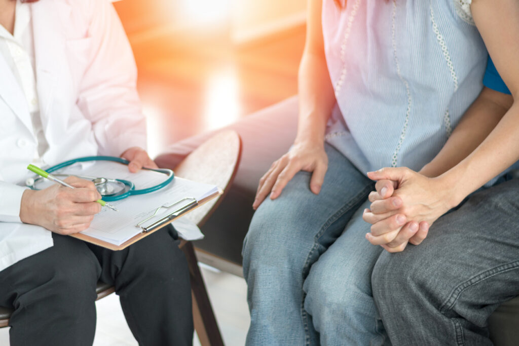 Problema de infertilidad con concepto de pareja matrimonial. Un médico de fertilidad o un endocrinólogo reproductivo con el hombre y las mujeres que sujetan la mano juntos en terapia consulta la sesión de incapacidad para embarazado