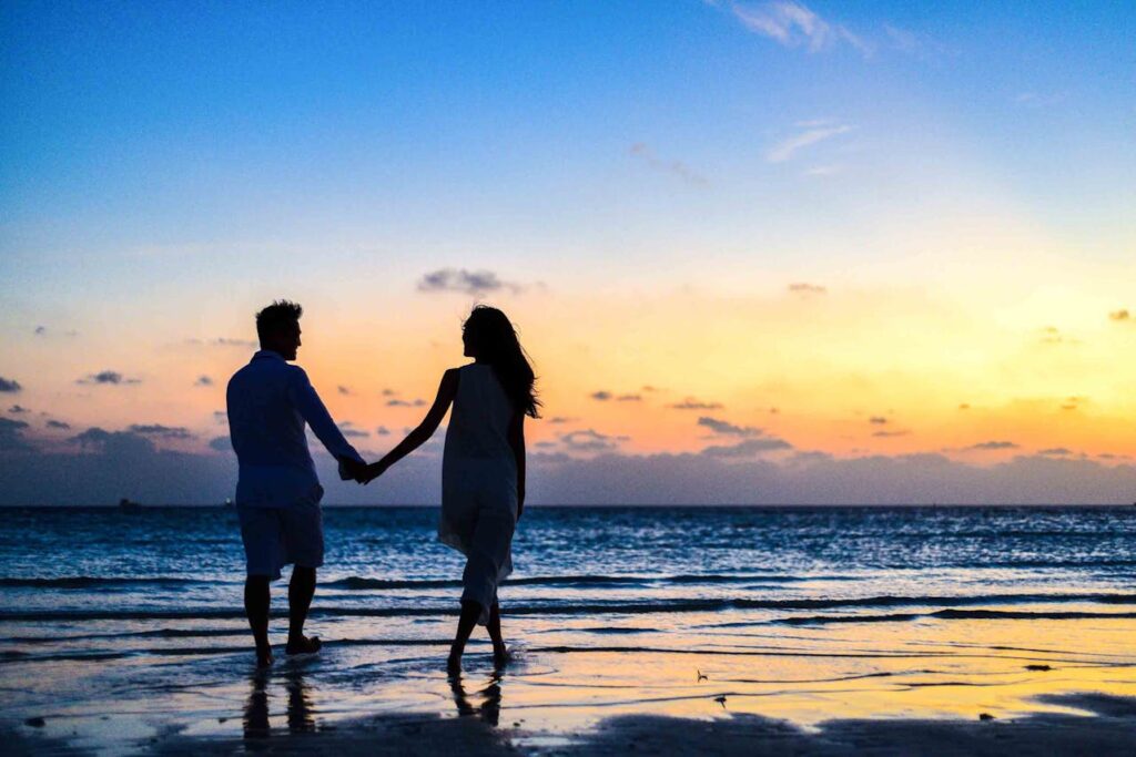 Pareja dando un paseo por la playa, pensando en el Impacto Psicológico de la FIV en su relación