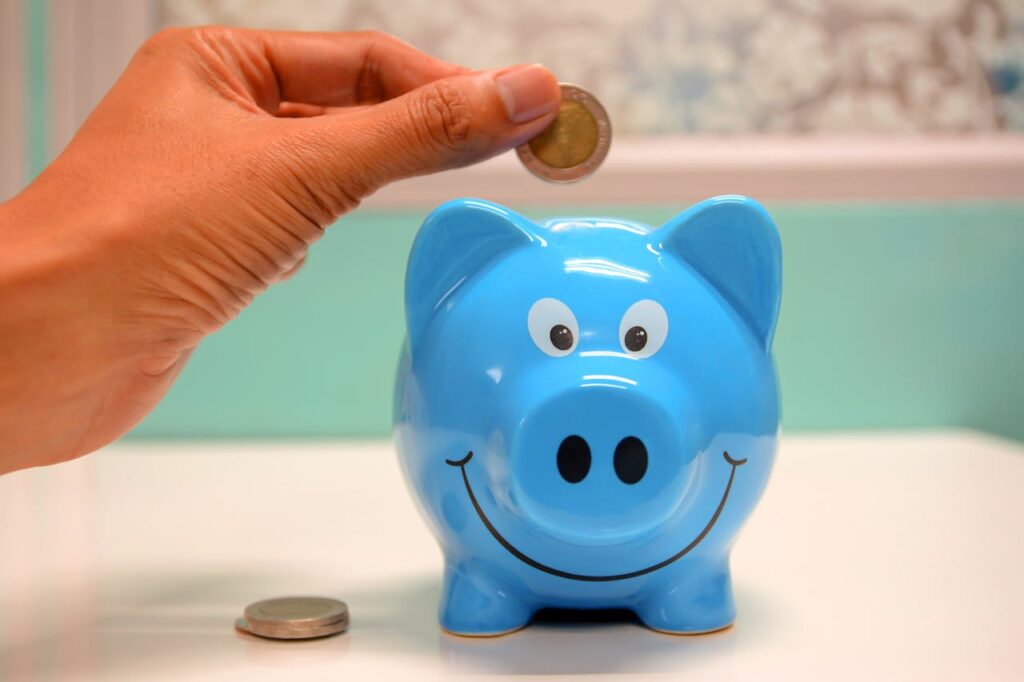 Persona metiendo dinero en una hucha de cerdito de color azul