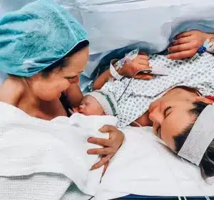 Two woman post birth in hospital theatre with baby
