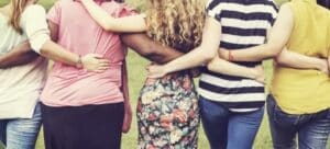 Five women from behind all hugging in a row