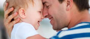 Man holding baby to his face, both are smiling