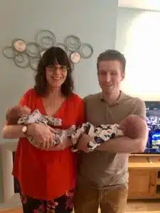 Man and woman smiling looking at camera while holding twins