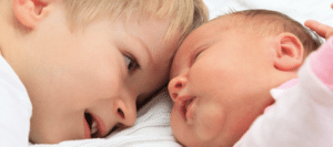 Baby laying next to child