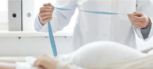 Doctor holding measuring tape to measure pregnant belly