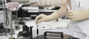 Gloved hands using test tube