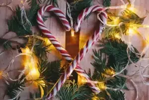 Candy cains crossed to make heart next to Christmas decorations