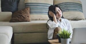 A woman sitting in front of a sofa, looking stressed about starting IVF treatment.