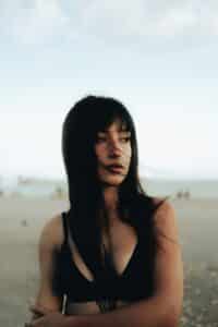 Woman on beach in bikini looking pensive