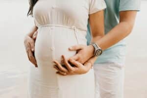 Man holding hands of pregnant woman from behind