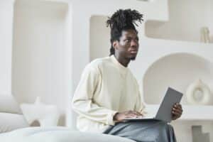 Man holding laptop looking quizzical